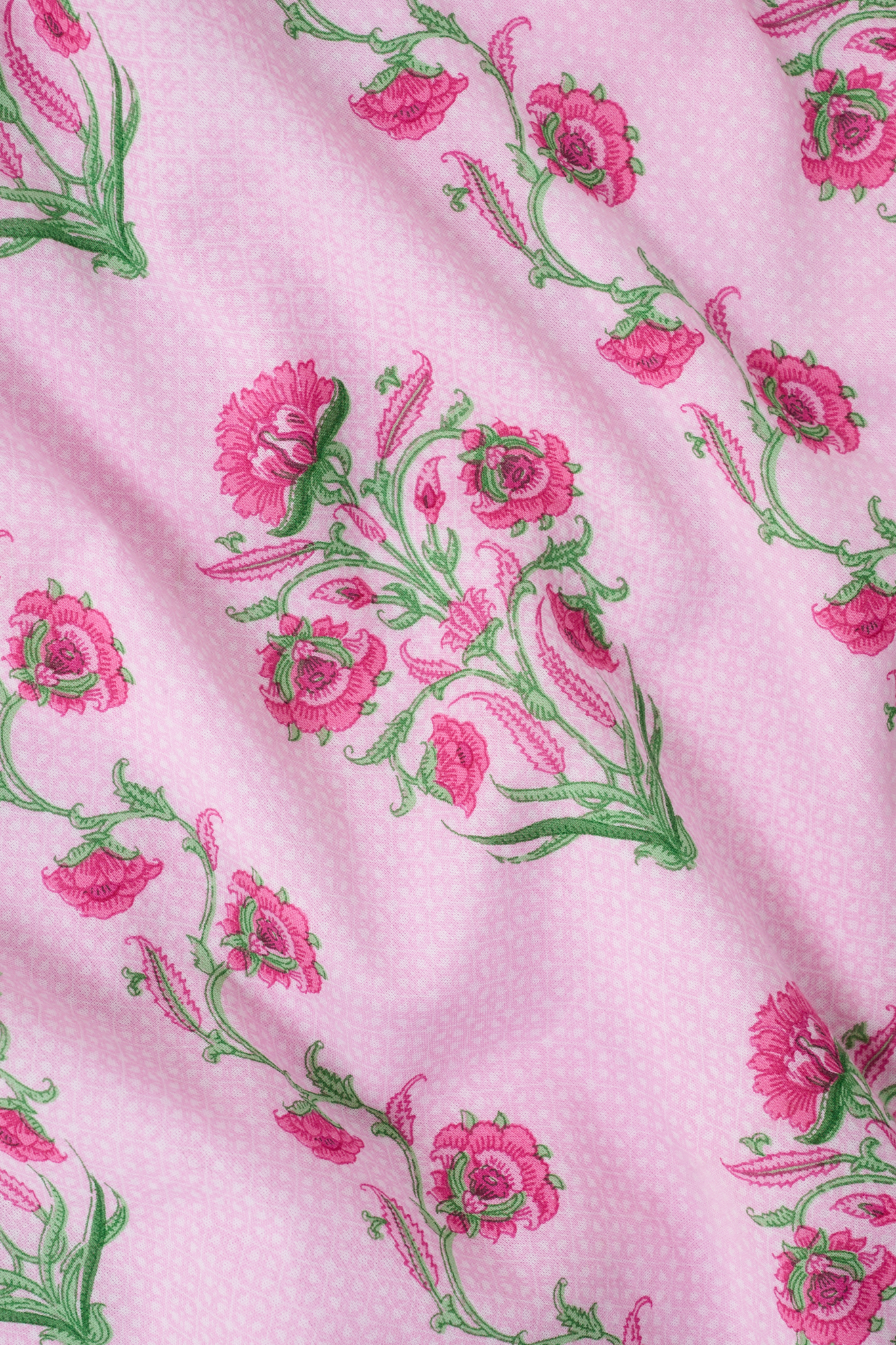 A woman with long brown hair wears the Roller Rabbit Lily Stripe Briella Dress, a loose cotton voile lounge dress with puffed short sleeves and a green and pink floral pattern, standing against a plain light background.