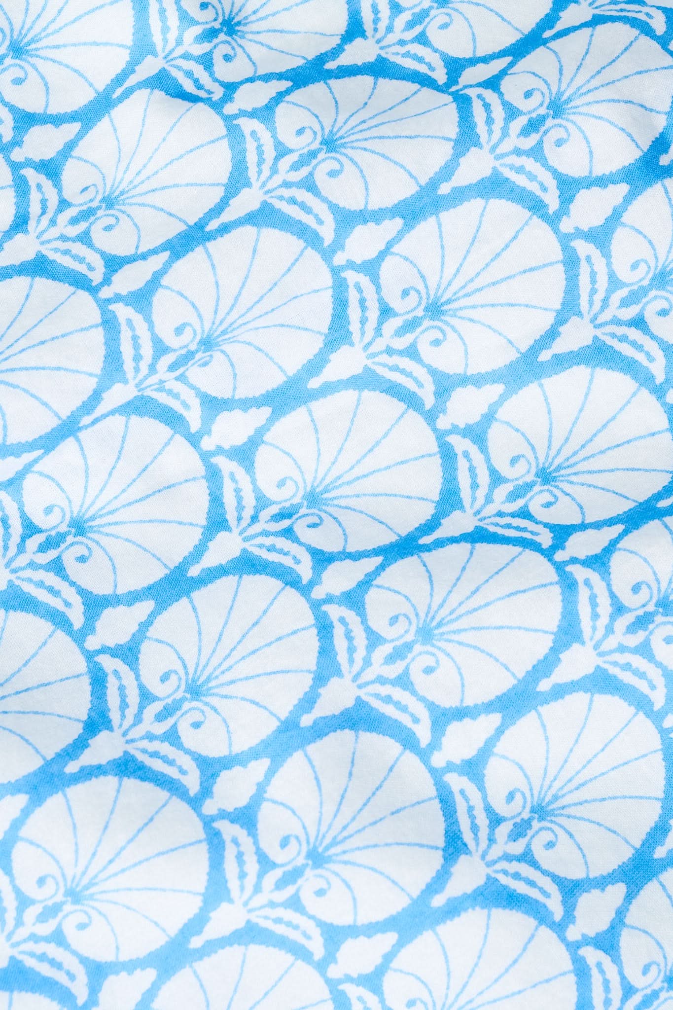The Fan Geo Shirt Dress by Roller Rabbit features blue and white cotton voile with a geometric, seashell-inspired fan print and leaf details—an oceanic look perfect for spring.