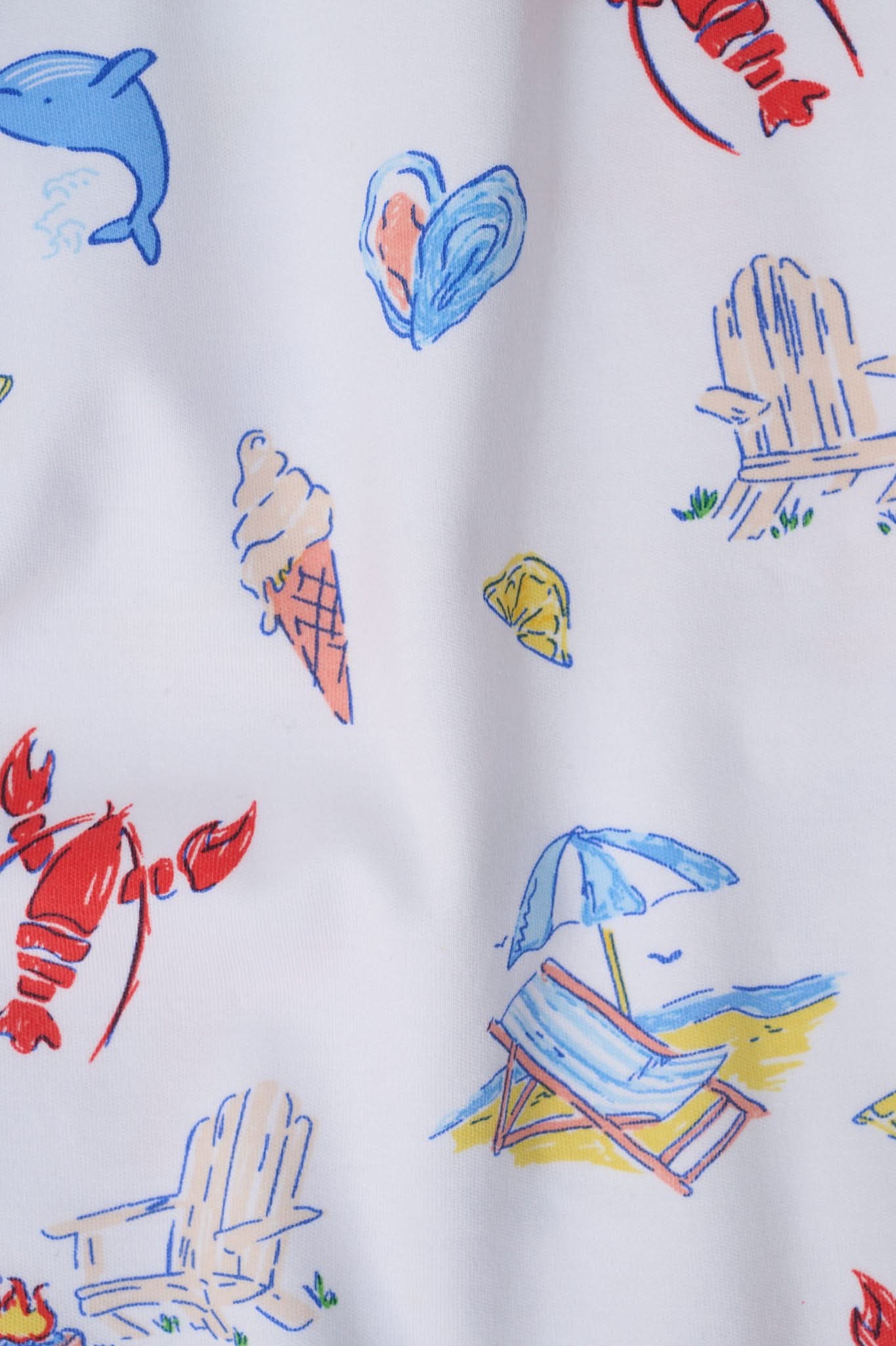 A woman stands barefoot in Roller Rabbit's Catch of the Day Polo Pajamas—short-sleeve, button-up PJs with matching shorts, both featuring a colorful seaside print—facing forward against a plain white background.