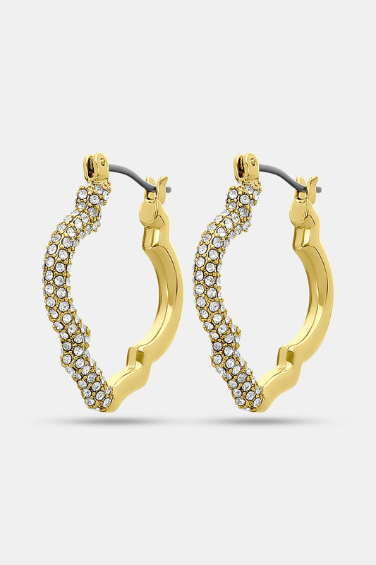 Geo Gem Earrings by Roller Rabbit are geometric hoops with a wavy design, adorned with small white gemstones along the front. These imitation gold earrings have a hinged clasp and are shown on a plain light background.