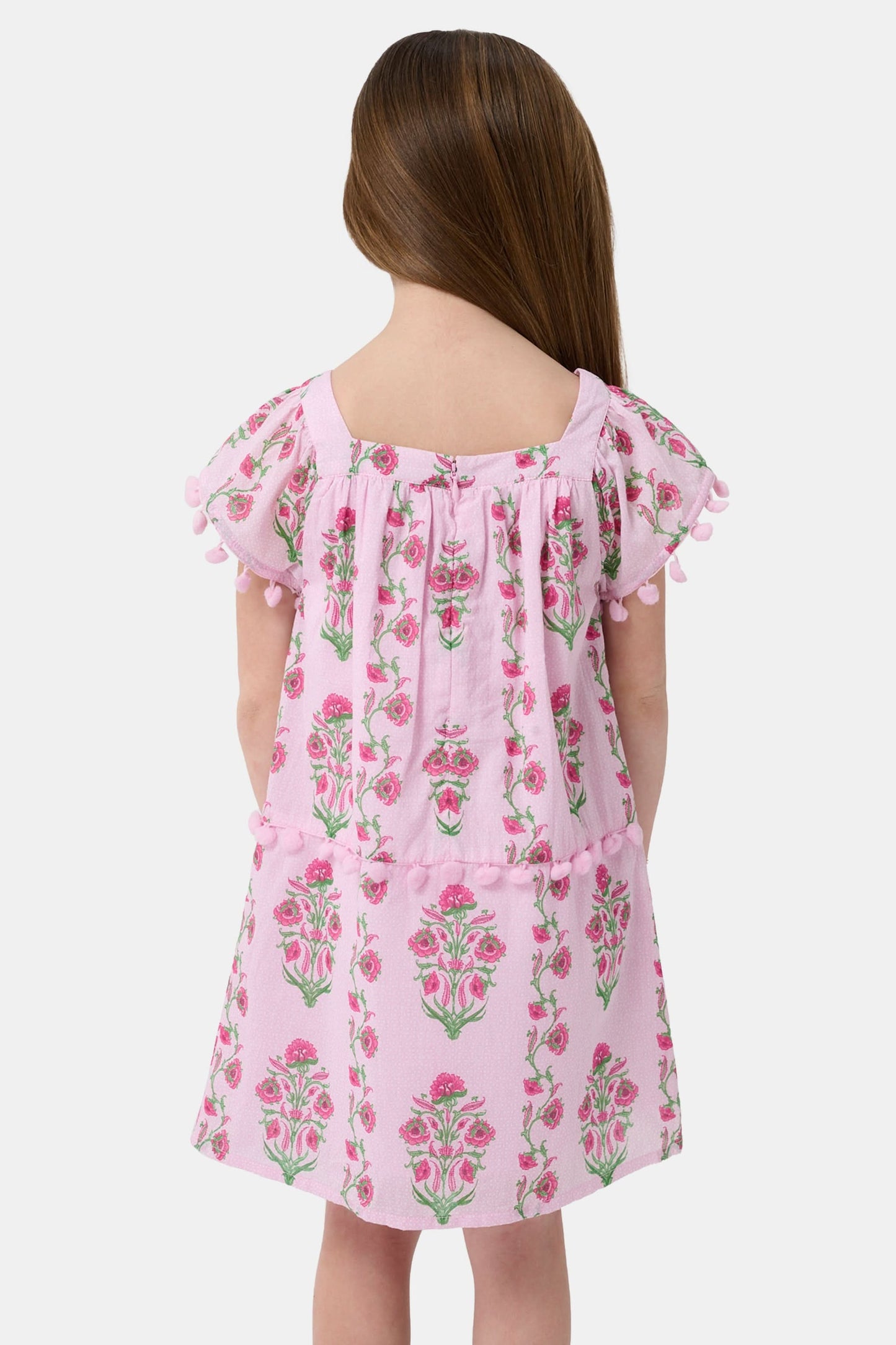 A young girl with long brown hair smiles, wearing the Roller Rabbit Kids Lily Stripe Oceana Dress. She stands with her hands on her hips against a plain light background.