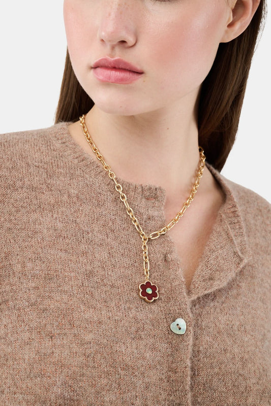 The Raya Floral Necklace by Roller Rabbit features a burgundy floral pendant with a green center on a gold chain, displayed against a white background.