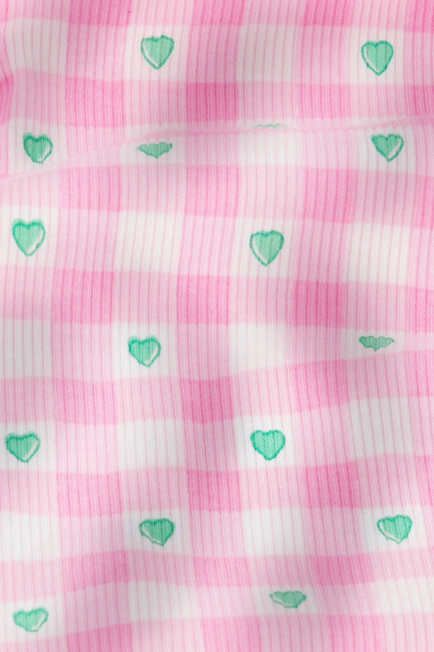 The Roller Rabbit Gingham Hearts Chrystie Bralette features pink and white striped ribbed cotton with small green hearts evenly spaced, plus a slightly wrinkled texture for added depth and gentle shadows.
