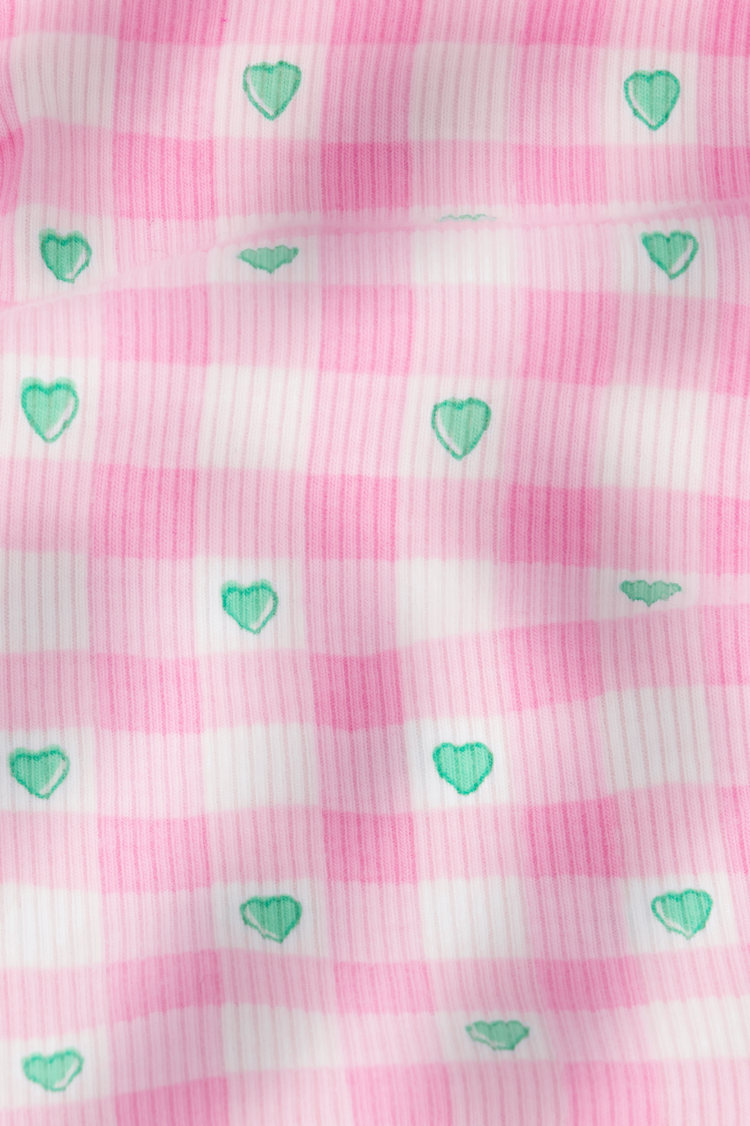The Roller Rabbit Gingham Hearts Chrystie Bralette features pink and white striped ribbed cotton with small green hearts evenly spaced, plus a slightly wrinkled texture for added depth and gentle shadows.