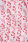 Wearing the Roller Rabbit Rosa Ditsy Monkey Hayden Pajamas—a pink and white set with a small anchor print, long-sleeve button-up top, and ruffled shorts—a person stands against a plain light background, smiling slightly.