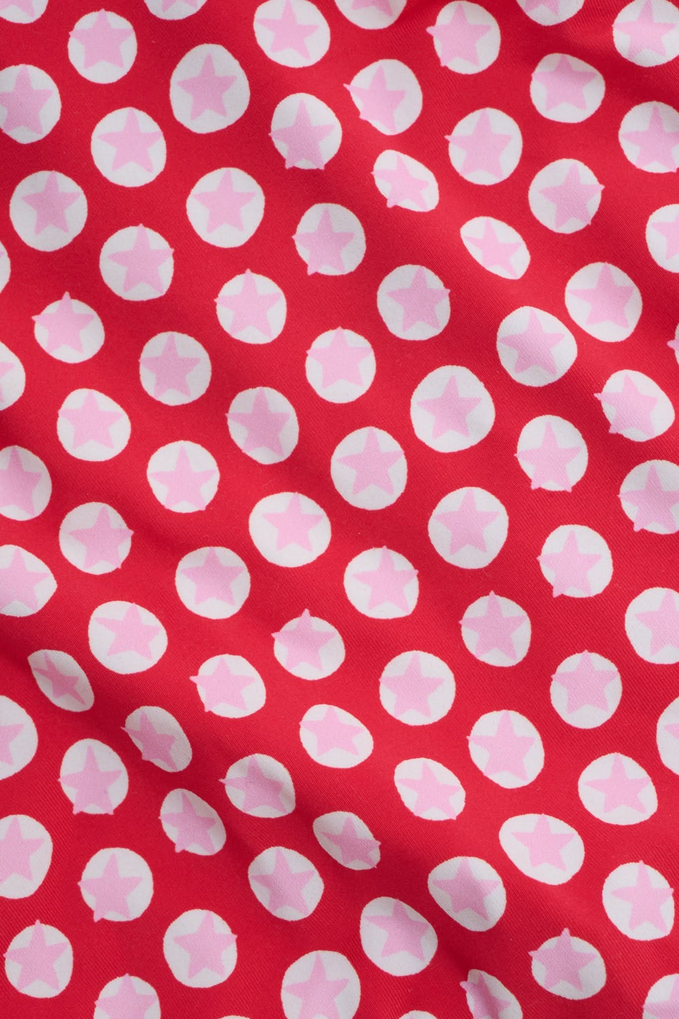 A person wears the Roller Rabbit Starry Dot Isa Bikini Bottom in red with white polka dots and adjustable hip ties, shown from mid-torso to upper thigh.