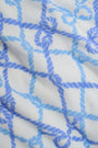 A person wears the Roller Rabbit Seaside Knots Mara Pant, featuring a tie waist and wide legs in loose white fabric with a light blue geometric chain pattern, paired with a matching top and white sandals against a plain white background.