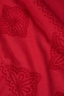 A woman with long curly hair wears the Roller Rabbit Monaco Geo Penelope Dress, a sleeveless, halter-neck, ankle-length red dress with subtle embroidery. She stands forward in open-toed, low-heeled sandals against a plain white background.