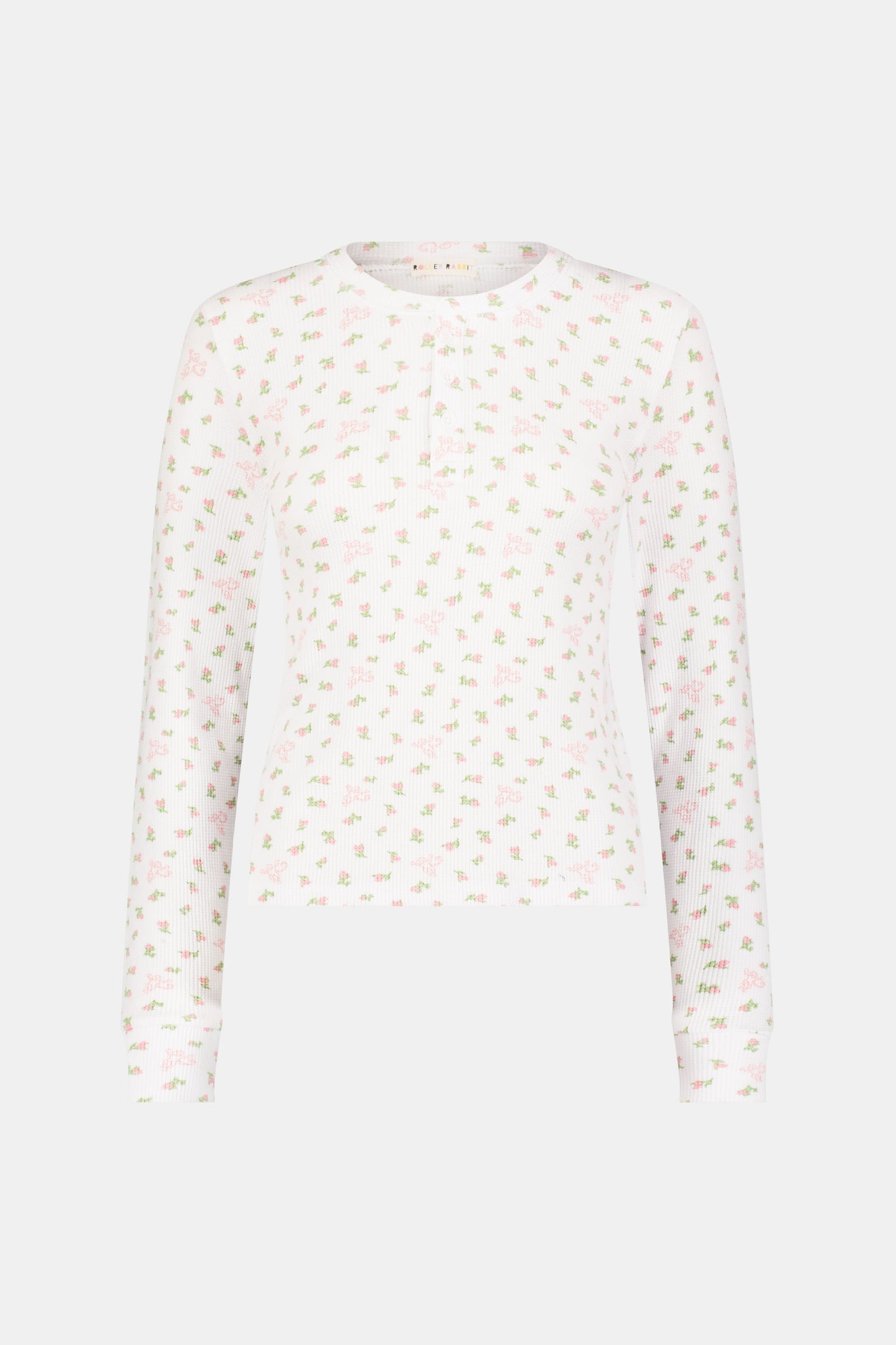 A woman wears the Mini Monkey Blossom Rosemary Top by Roller Rabbit, featuring a white pima cotton fabric with a small pink floral pattern, standing facing forward against a light background with her hands at her sides.