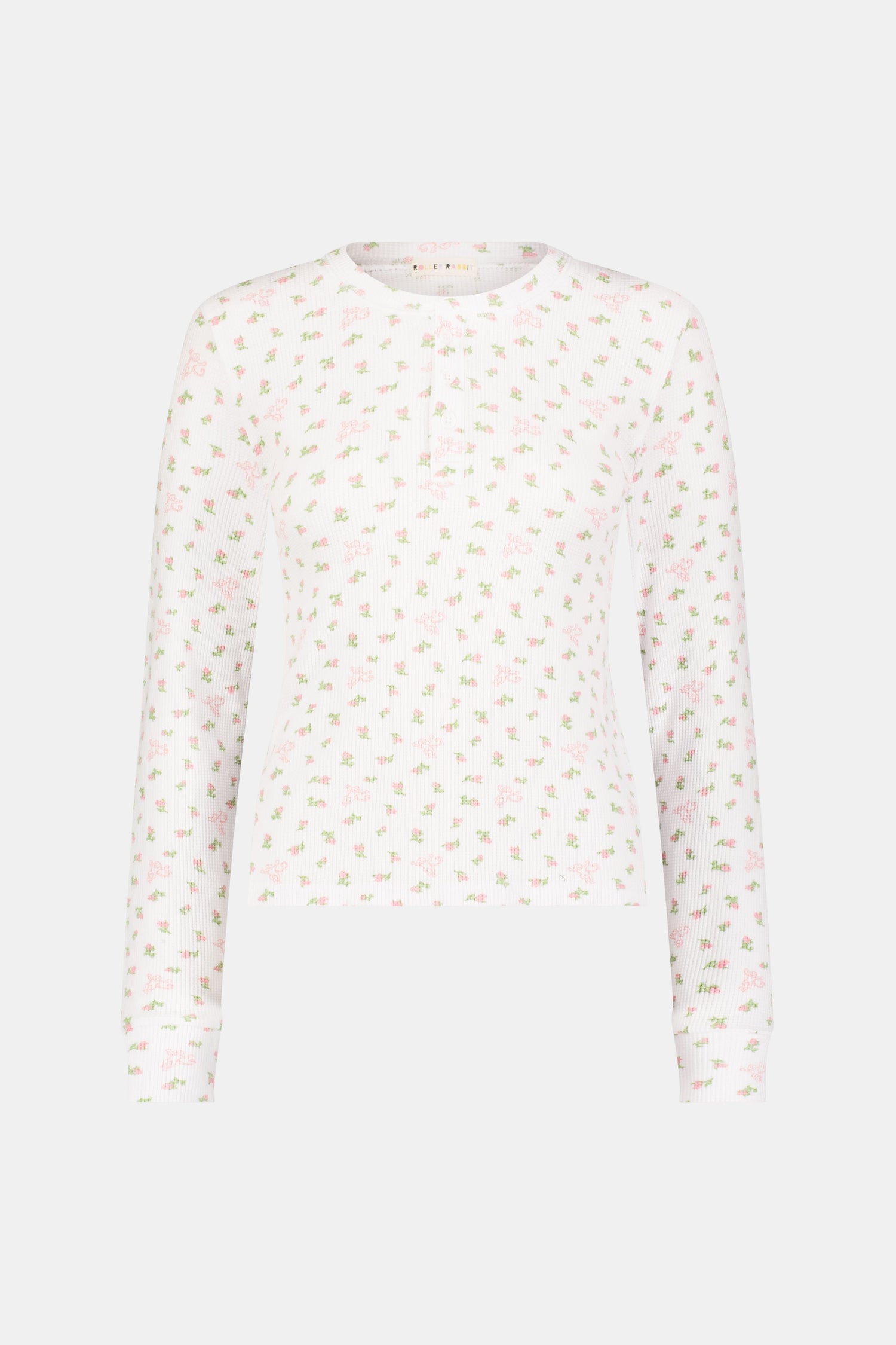 A woman wears the Mini Monkey Blossom Rosemary Top by Roller Rabbit, featuring a white pima cotton fabric with a small pink floral pattern, standing facing forward against a light background with her hands at her sides.