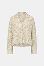 The Space Dye Dhalia Cardigan is a cream, button-up baby alpaca cardigan with a blue speckled pattern, long sleeves, and a collar, shown on a plain white background.