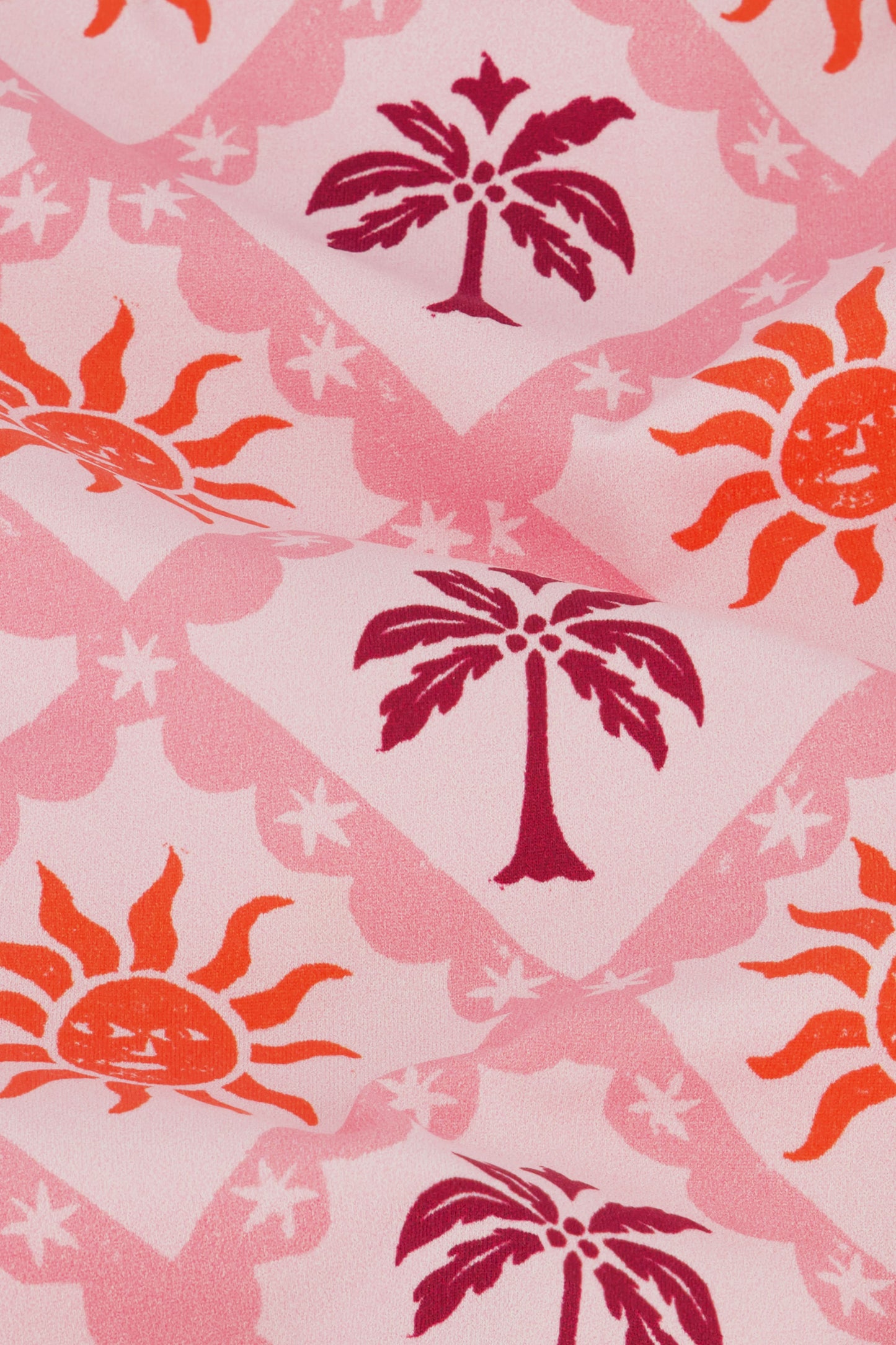 The Kids Sunny Days Rashguard by Roller Rabbit is a pink long-sleeve rashguard with a quarter-zip front, decorated with orange suns and red palm trees on a light pink background for playful sun protection.