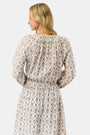 A woman with blonde hair wears the Infinity Floral Embroidery Stevie Top by Roller Rabbit, featuring vintage floral embroidery and a drawstring neckline, standing against a plain white background and smiling softly.