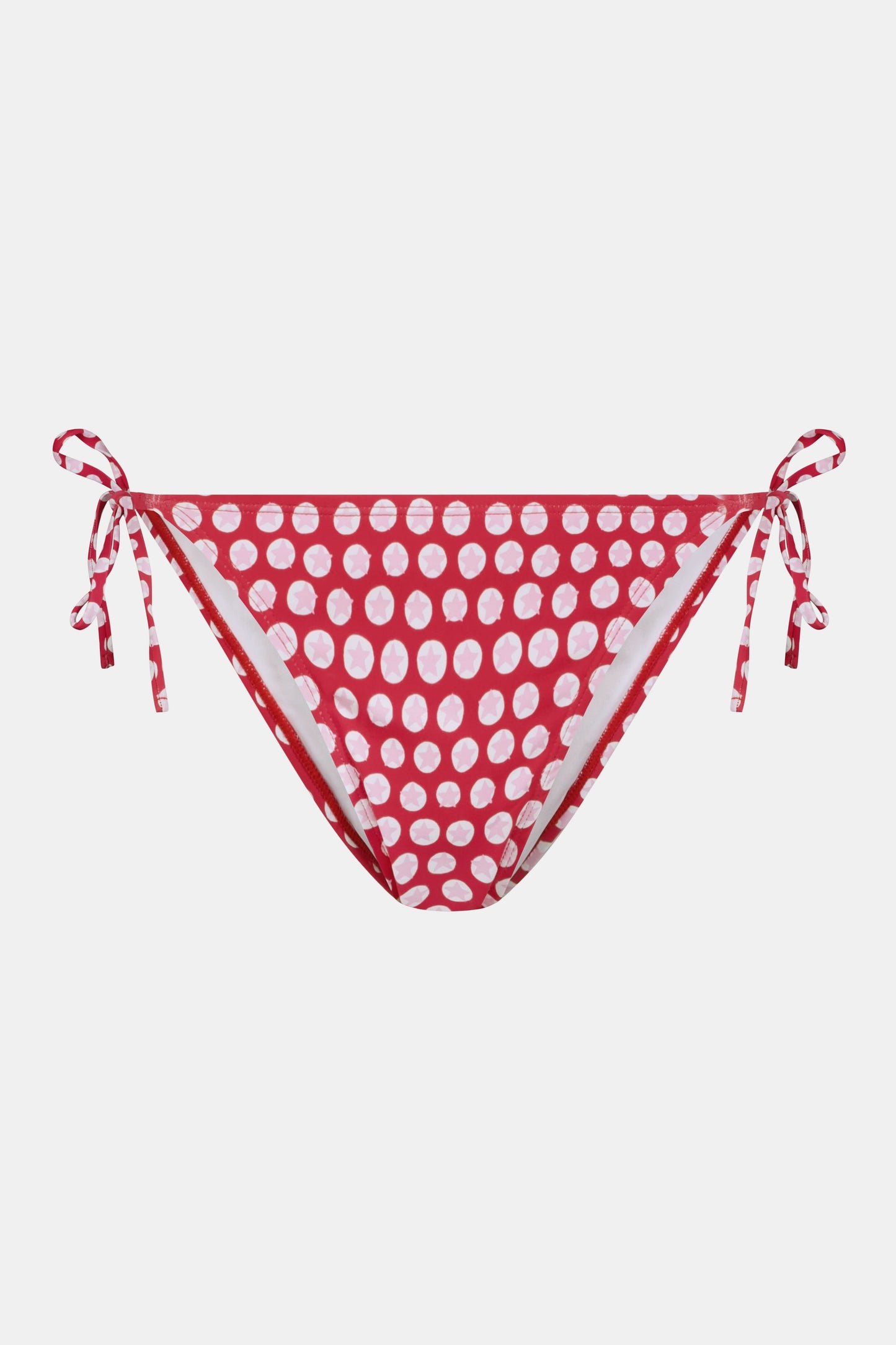 A person wears the Roller Rabbit Starry Dot Isa Bikini Bottom in red with white polka dots and adjustable hip ties, shown from mid-torso to upper thigh.