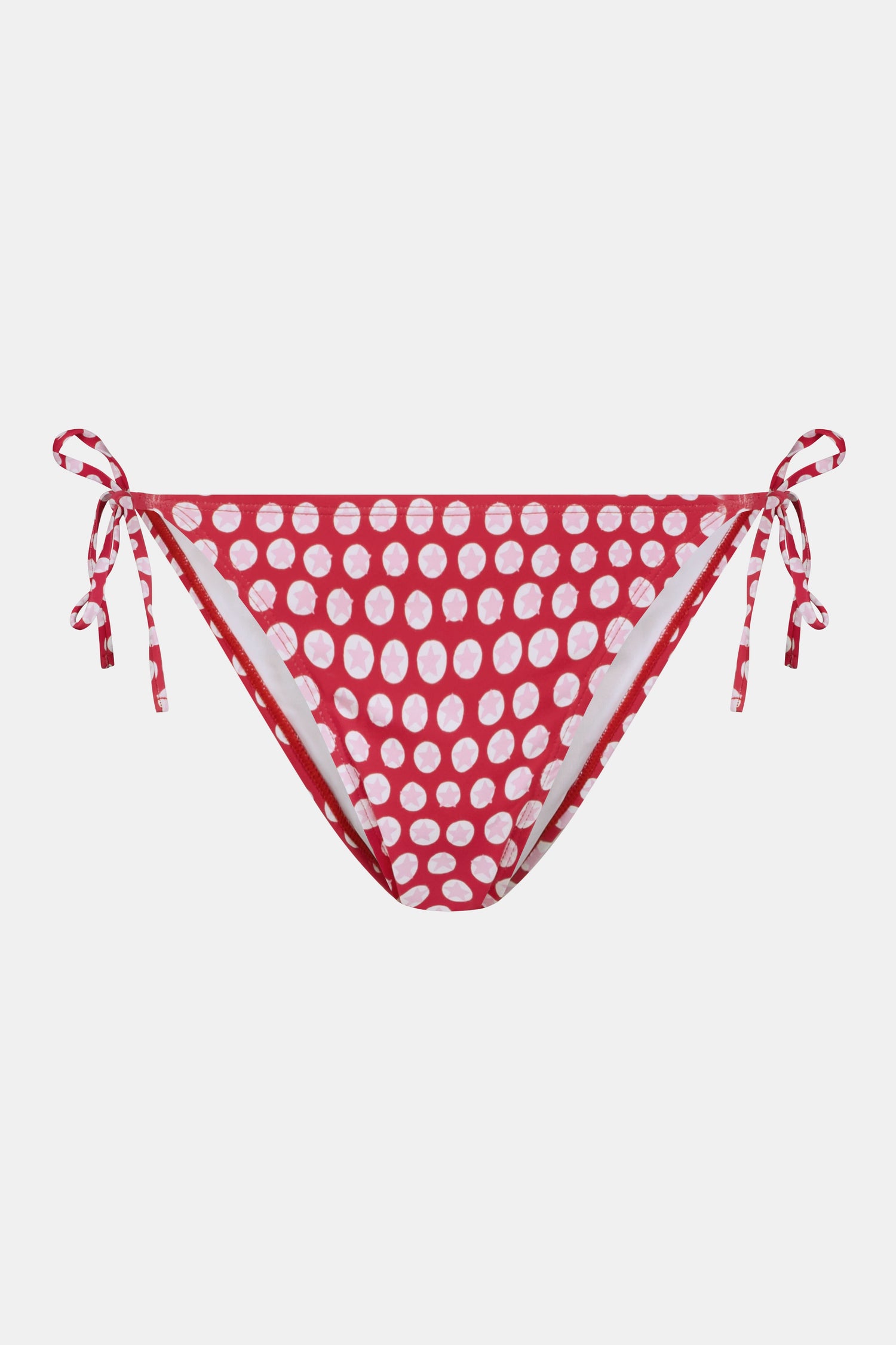 A person wears the Roller Rabbit Starry Dot Isa Bikini Bottom in red with white polka dots and adjustable hip ties, shown from mid-torso to upper thigh.