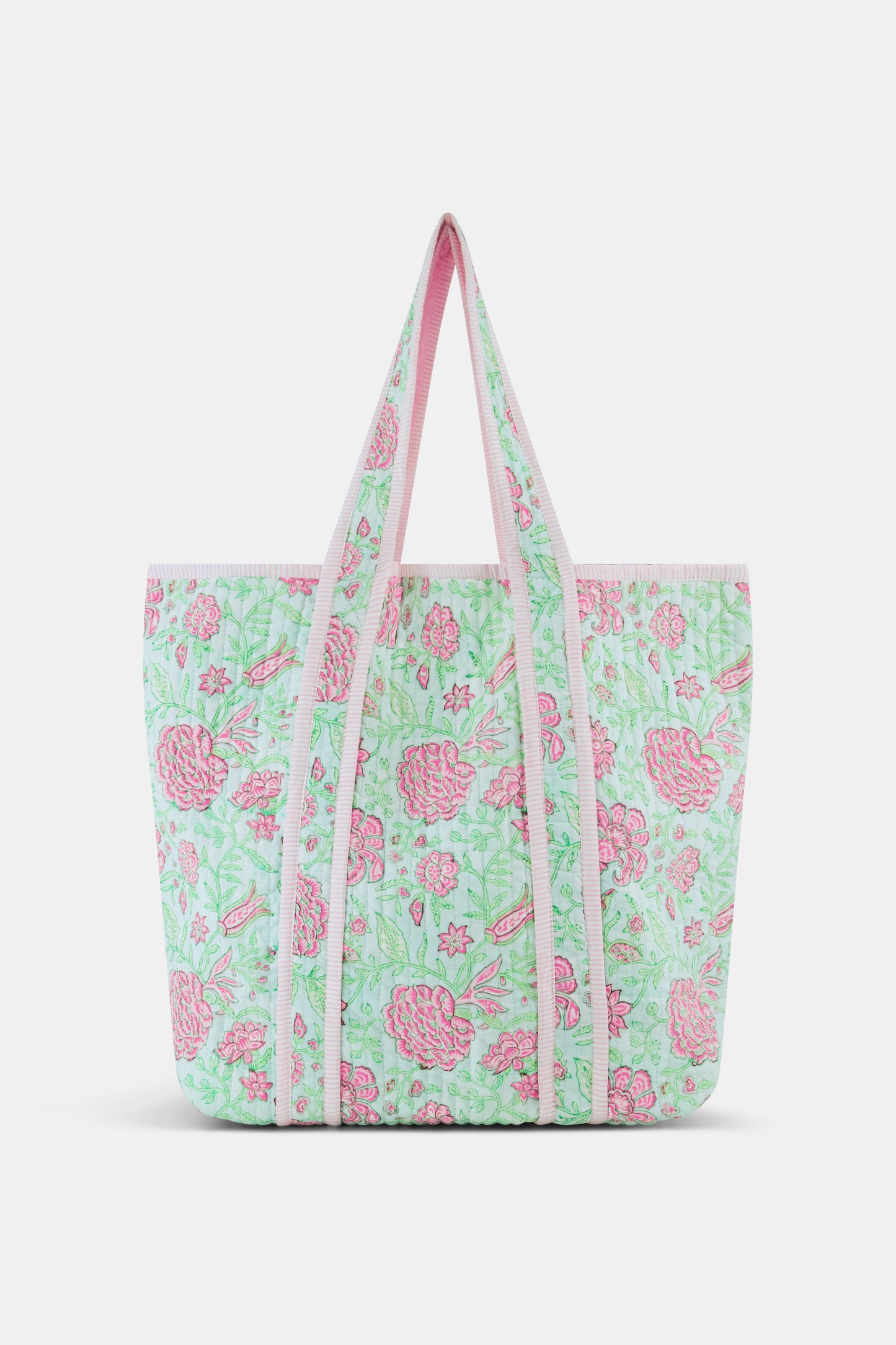 The Roller Rabbit Camellia Block Quilted Tote features pink and green floral patterns, a pale pink interior lining, and long white handles, shown on a plain white background.