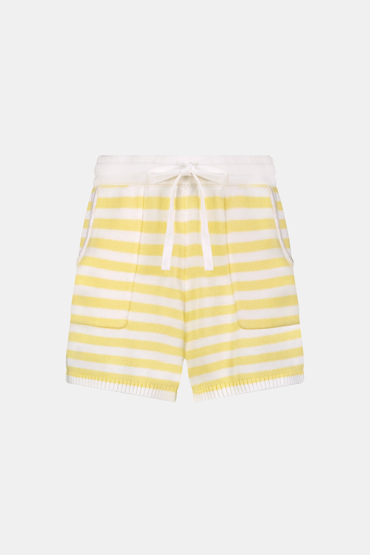 A person wears Roller Rabbit’s Striped Brie Short—a knit yellow and white horizontal striped short with a white drawstring at the elastic waistband and hands tucked in the front pockets.