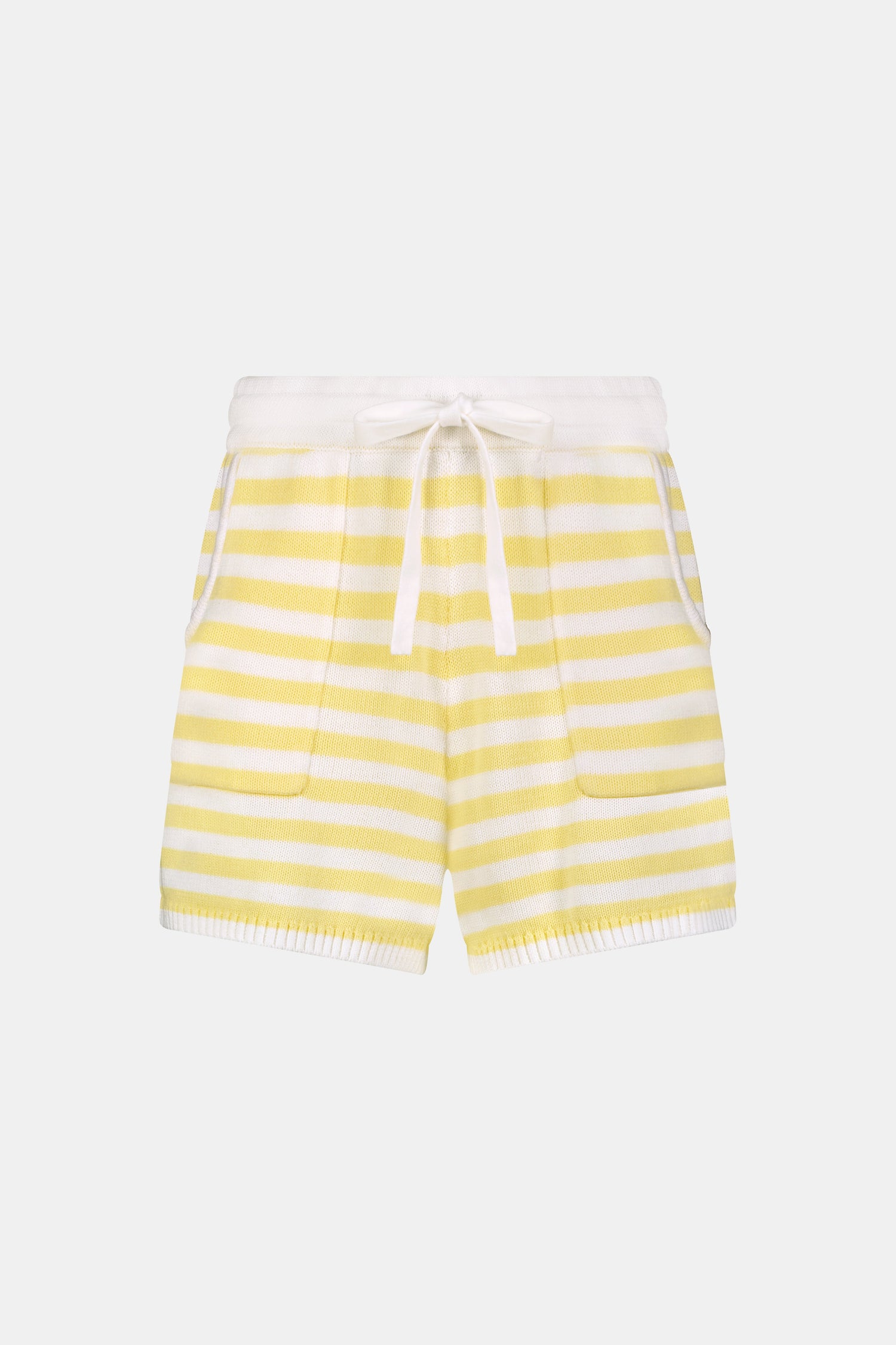 A person wears Roller Rabbit’s Striped Brie Short—a knit yellow and white horizontal striped short with a white drawstring at the elastic waistband and hands tucked in the front pockets.