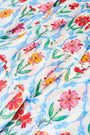 A close-up of the Roller Rabbit Infinity Floral Siggy Skirt, a crinkle chiffon mini with ruffles, featuring red, yellow, pink, and green florals on white. The skirt is styled with a white top.