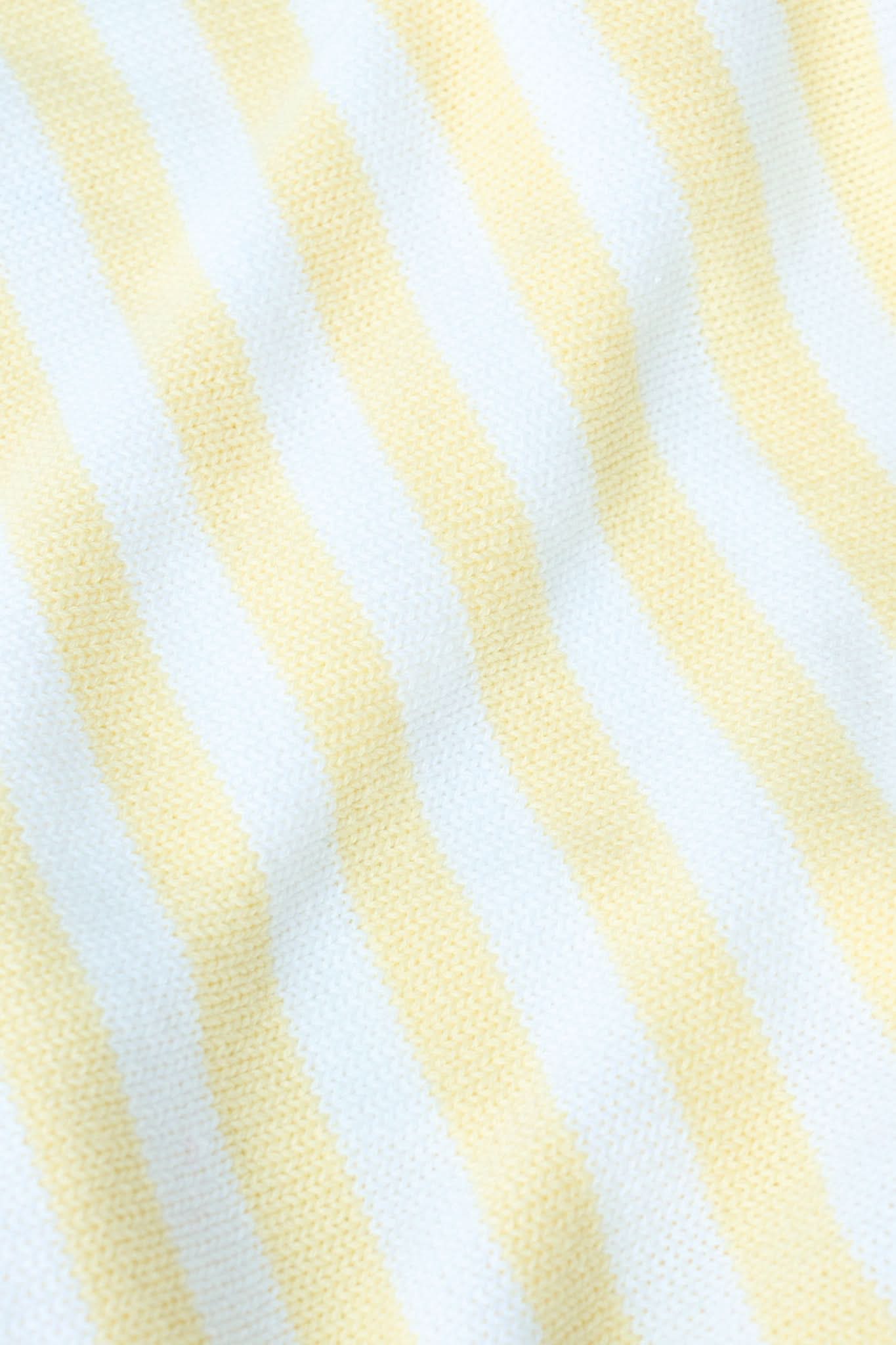 A young woman with light skin and long brown hair wears the Roller Rabbit Striped Rocio Sweater, a pastel yellow, lightweight cotton knit with a wide V-neck and collar. She pairs it with matching drawstring pants and gazes slightly to the side.