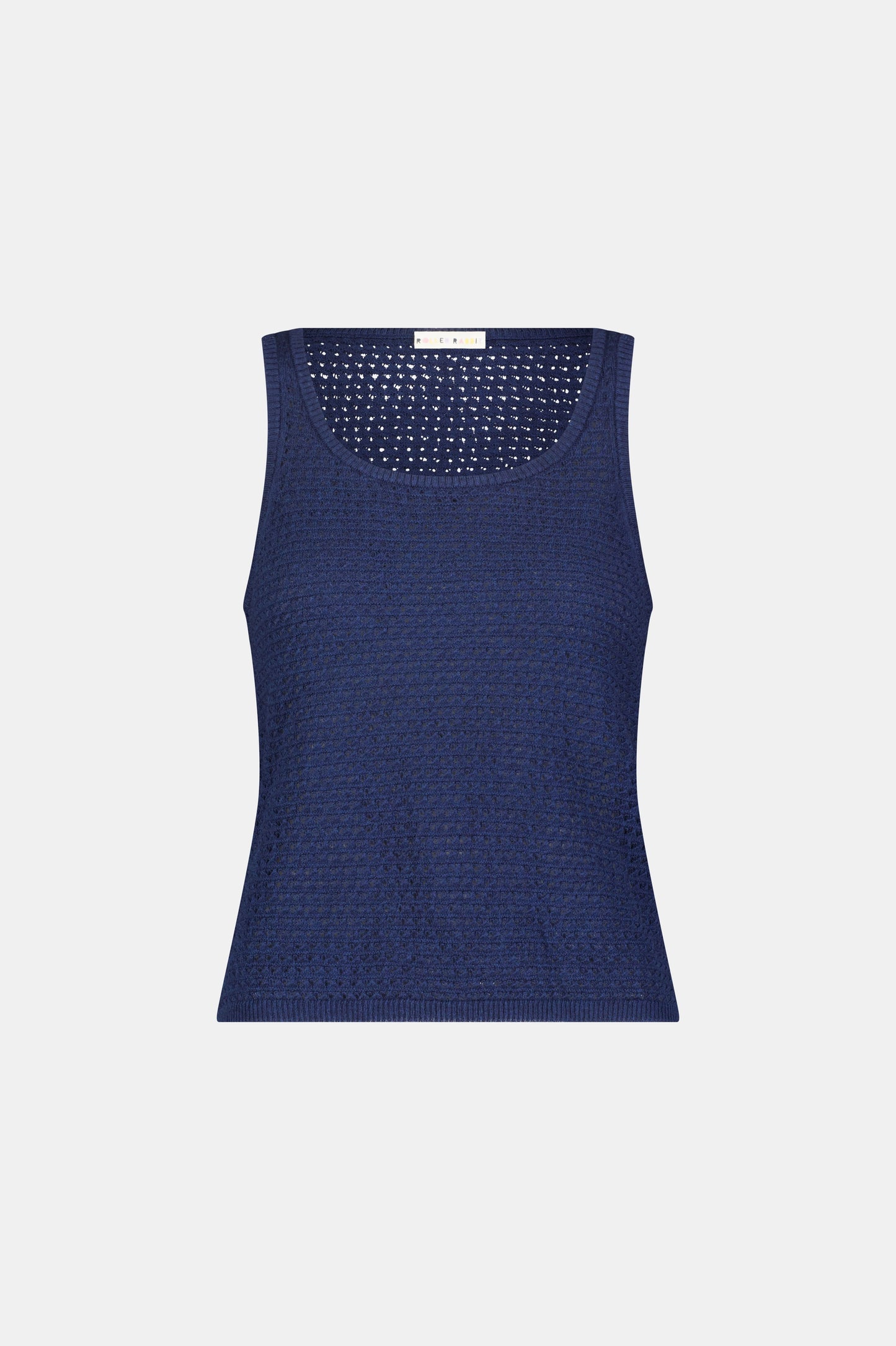 A woman wears the Roller Rabbit Pointelle Sasha Sweater Tank in navy with a textured open-weave design, paired with white shorts featuring blue floral prints. She is shown from shoulders to waist, looking slightly to the side.