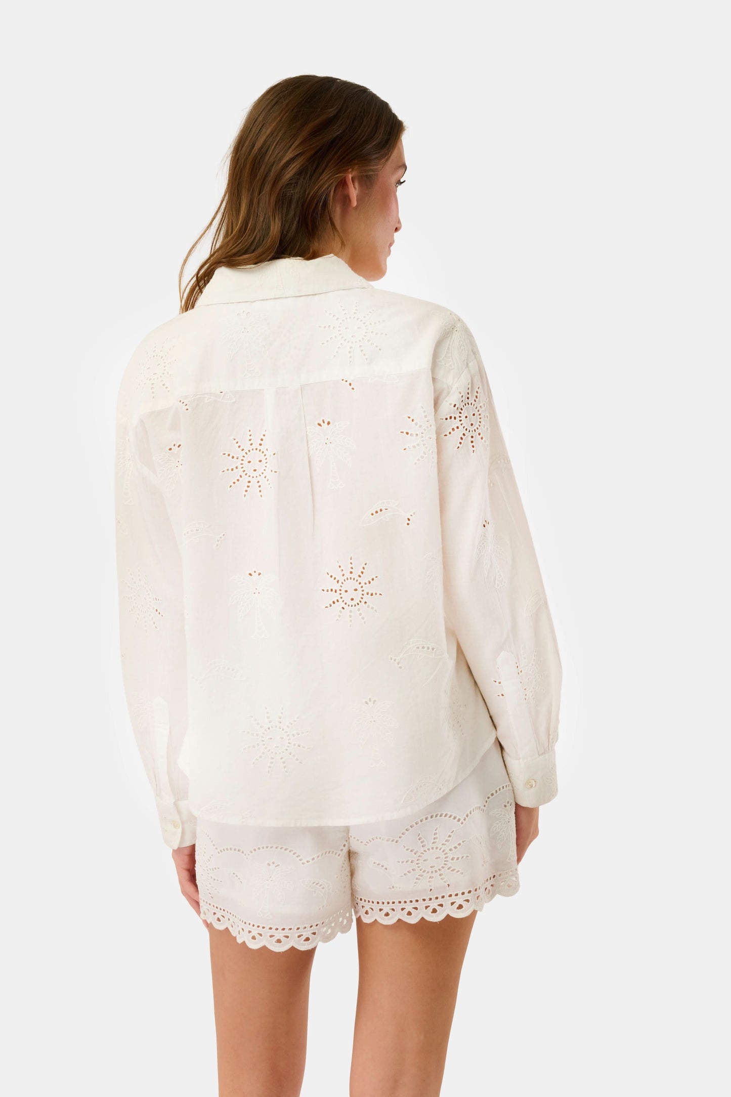 A woman in a straw hat and white scalloped shorts wears the Roller Rabbit Sunny Days Eyelet Girlfriend Shirt, standing against a plain light background.