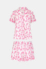 The Gigi Giraffe Polo Pajamas feature a short-sleeved, button-up top and matching shorts in soft pima cotton with a white background and playful pink giraffes—perfect for stylish, comfortable lounging.