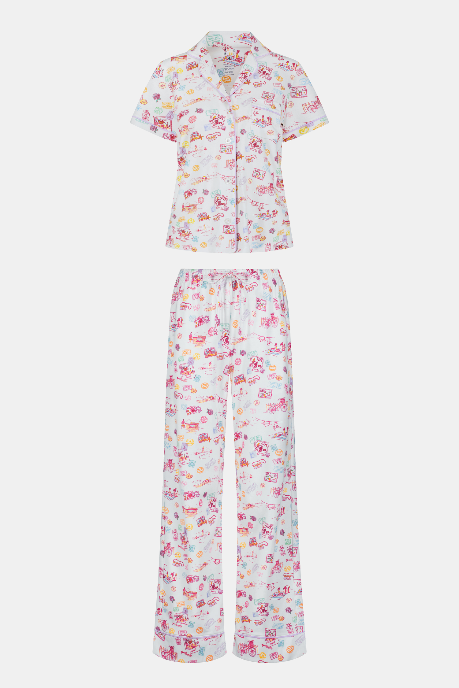 A woman with curly hair models the Roller Rabbit Summer Memories Fiora Pajamas, a Pima cotton set with a colorful sushi print, including a short-sleeve button-up top and long pants, against a white background.