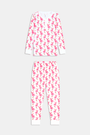 A young girl smiles barefoot in Roller Rabbit’s Kids Romy the Rabbit Pajamas, a soft Pima cotton long-sleeve set with a playful rabbit print; her brown hair frames her face against a simple, light background.