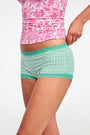 The Roller Rabbit Classic Core Boyshort 4 Pack includes four pairs of girls' underwear in fun patterns—green diamond, white with blue florals, mint with hearts, and light blue floral—all made from soft modal fabric for comfort.