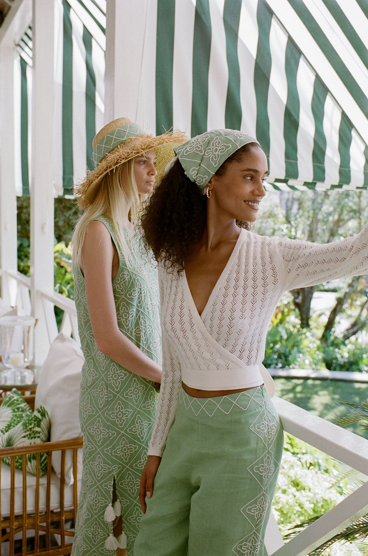 A woman wearing the Roller Rabbit Pointelle Cassidy Sweater paired with green high-waisted pants featuring white embroidered details, standing against a plain light background.
