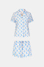 A woman wears the Roller Rabbit Romy the Rabbit Livy Set, a light blue cotton two-piece loungewear featuring a colorful bunny print, as she stands smiling against a plain white background.