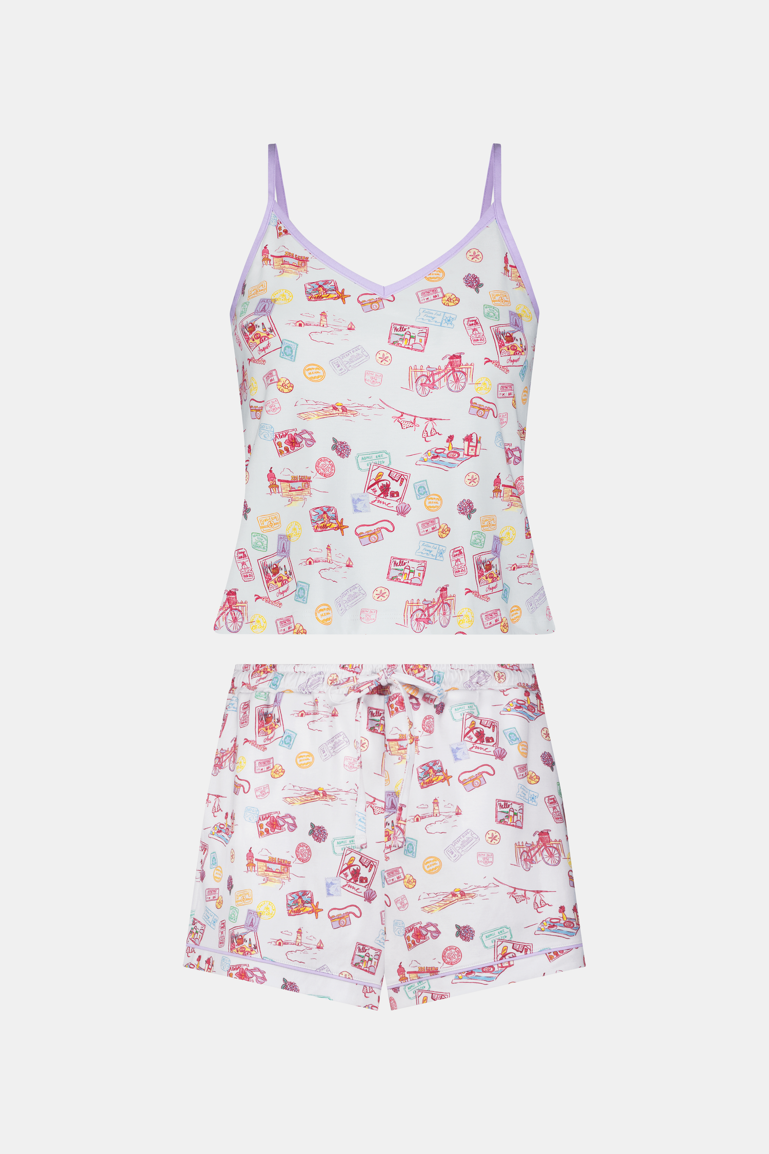 A woman wears the Roller Rabbit Summer Memories Mischa Set, a 100 Pima cotton cami tank and boxer set with a pastel travel icon print on white, standing against a light background.