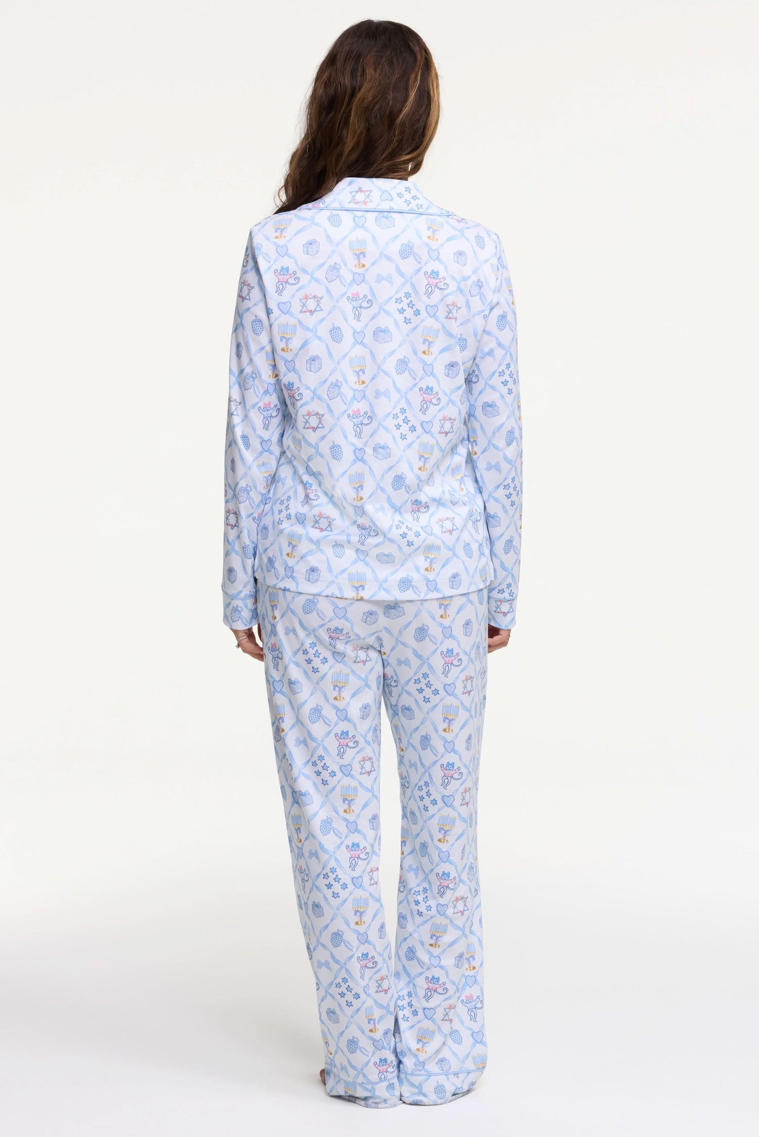 A woman smiles barefoot on a white background, hands in pockets, wearing Roller Rabbit's Starry Nights Lattice Long Sleeve Polo Pajamas—cozy loungewear crafted from soft Pima cotton.