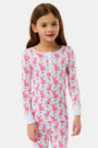 A young girl smiles barefoot in Roller Rabbit’s Kids Romy the Rabbit Pajamas, a soft Pima cotton long-sleeve set with a playful rabbit print; her brown hair frames her face against a simple, light background.
