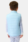 A young child with short brown hair is seen from behind, wearing the Kids Pop Stars Kiana Reversible Puffer Vest over white pajamas with a blue heart pattern, standing against a plain light background.