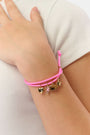 The Roller Rabbit Icon Party Charm Bracelet is a pink adjustable bracelet with five gold-tone charms—a heart, unicorn, butterfly, cat, and star—shown on a plain white background.