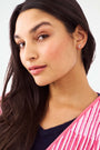 The Icon Party Earring Pack by Roller Rabbit features four pairs of gold and pink icon earrings—whales, hearts, elephants, and unicorns—arranged in two rows on a white background for a fun, playful style.