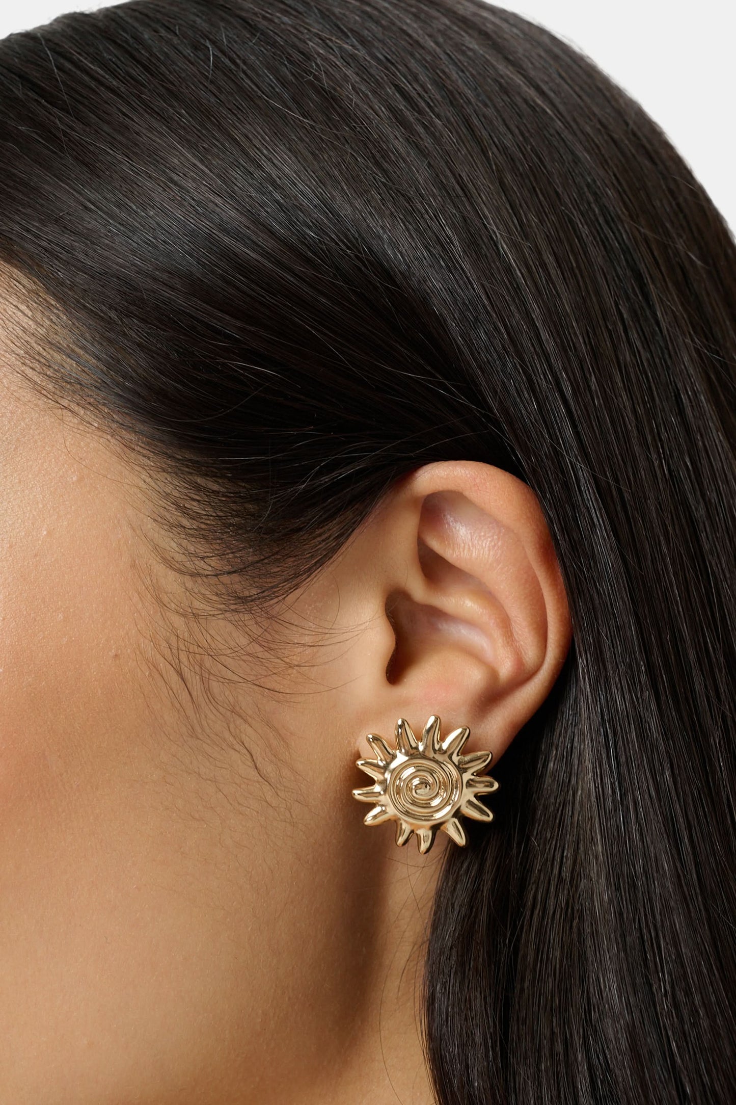 Roller Rabbit's Sunshine Stud Earrings showcase a gold sun-shaped design with a central spiral, displayed on a plain white background.