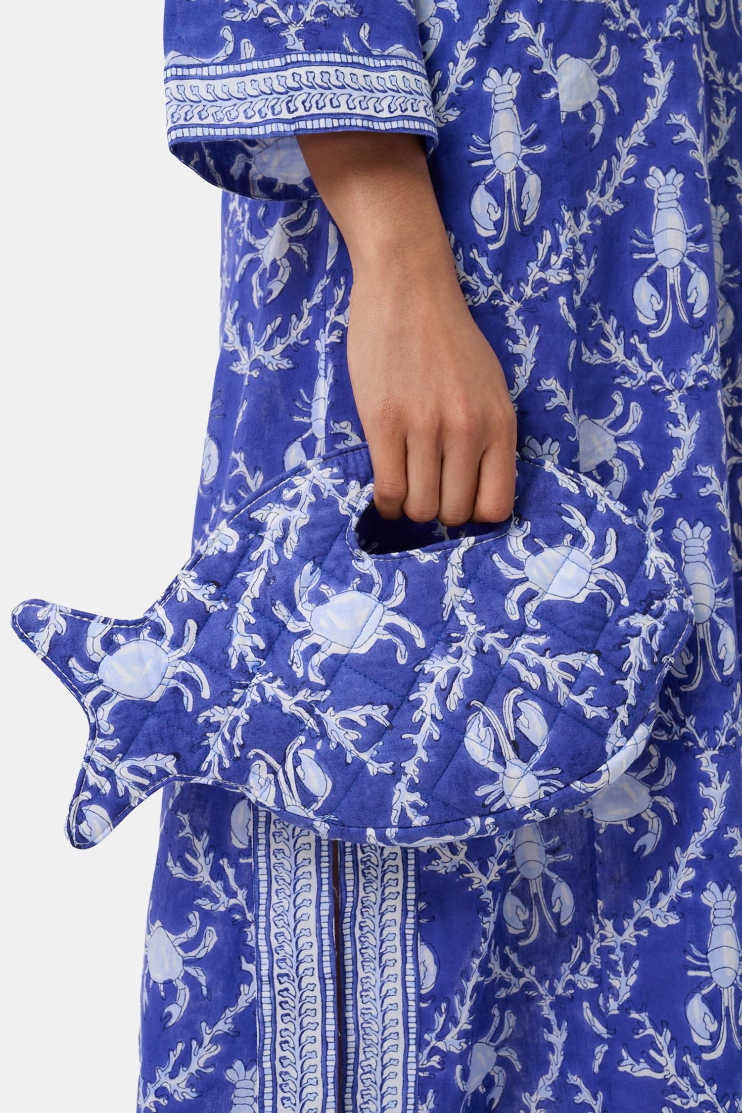The Roller Rabbit Lobster Trellis Fish Purse is a blue purse with a handle, decorated with lighter blue lobster and coral patterns.