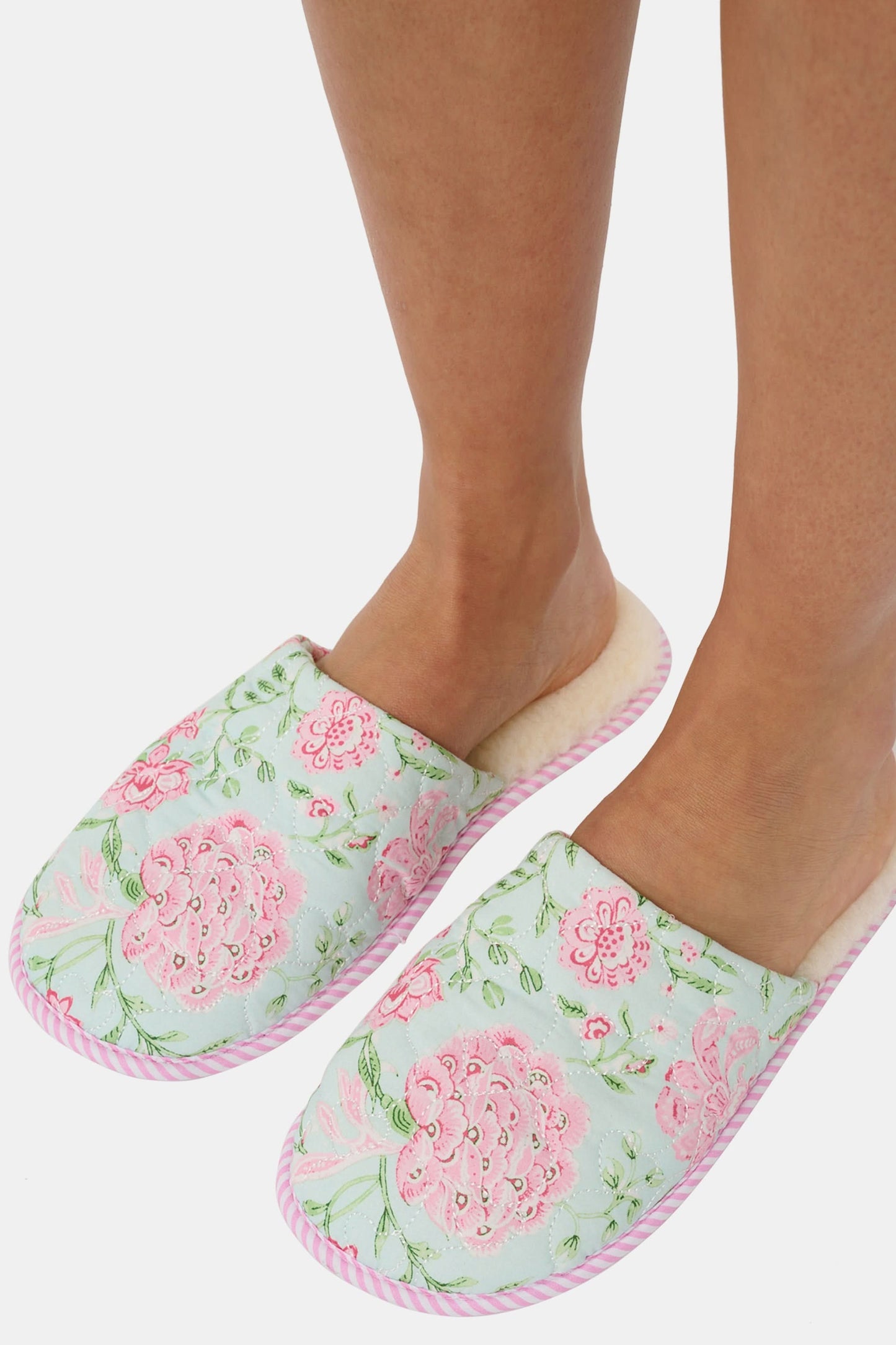 The Roller Rabbit Camellia Block Quilted Slippers are cozy, backless cotton slippers featuring a pink and green floral pattern on a light background, pink and white striped trim, and a soft cream-colored lining.