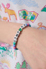The Roller Rabbit Camp RR Besties Bracelet features pink, blue, and green beads, a blue star bead, white letter beads spelling CAMP R R with a gold-edged green heart as the 