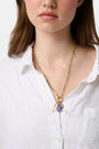 Roller Rabbit's Coastal Charm Necklace features a gold-tone chain with a white shell, blue fish, and gold spiral shell pendant—perfect for summer style—shown on a plain white background.