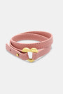 The Heather Love Bracelet by Roller Rabbit features pink leather with white stitching and an imitation gold heart-shaped clasp, shown coiled on a plain light background.