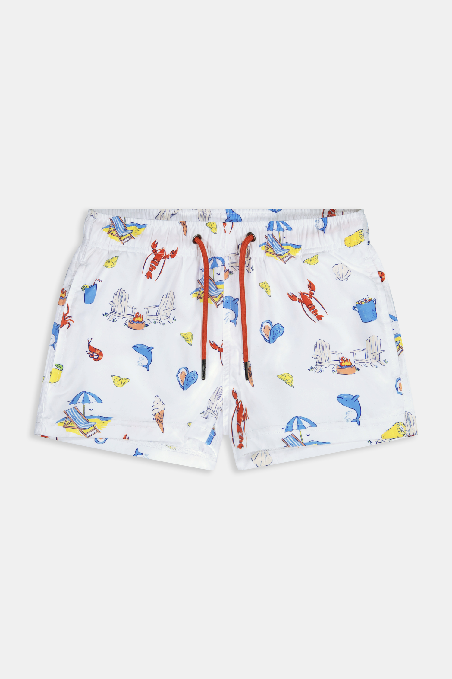 A young boy smiles barefoot in front of a cream-colored vehicle, wearing Roller Rabbit Boys Catch of the Day Shortie Swim Trunk with colorful prints, while another child sits partially visible beside him.