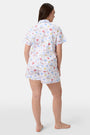 A woman stands barefoot in Roller Rabbit's Catch of the Day Polo Pajamas—short-sleeve, button-up PJs with matching shorts, both featuring a colorful seaside print—facing forward against a plain white background.