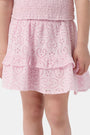 A young child wears the Roller Rabbit Kids Clover Eyelet Emry Skirt in light pink with ruffles and a matching smocked top, standing with their left arm slightly bent against a plain white background.