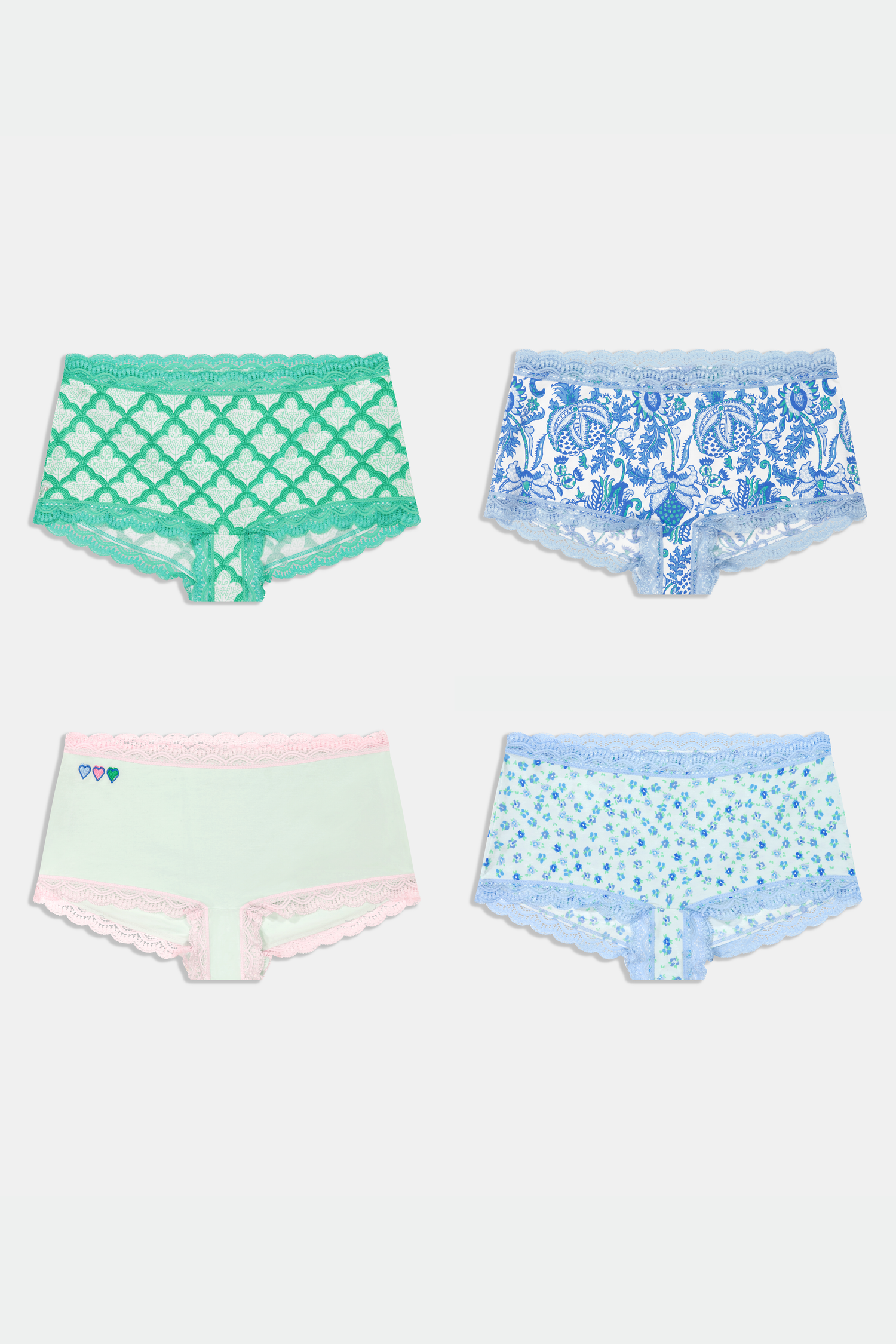 The Roller Rabbit Classic Core Boyshort 4 Pack includes four pairs of girls' underwear in fun patterns—green diamond, white with blue florals, mint with hearts, and light blue floral—all made from soft modal fabric for comfort.