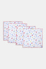 The Catch of the Day Napkin Set Of 4 by Roller Rabbit features white linen napkins with red scalloped edges, showcasing playful sea, beach, and ice cream prints in blue, red, and yellow. The napkins are arranged slightly overlapping.
