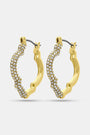 Geo Gem Earrings by Roller Rabbit are geometric hoops with a wavy design, adorned with small white gemstones along the front. These imitation gold earrings have a hinged clasp and are shown on a plain light background.
